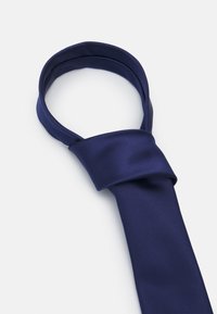 Cravate en soie marine, présentant une texture lisse et un design classique avec une section nouée pour un enfilage facile.