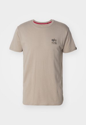 Beige bomulls t-shirt med rund halsringning och korta ärmar. Anmärkningsvärda detaljer inkluderar en svart logotyp på bröstet och en röd inre krage.