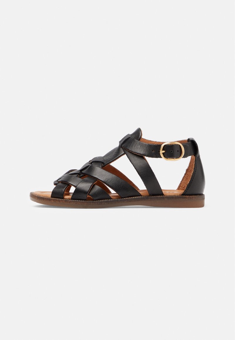 Černá kožená sandál s křížovými pásky, plochou podrážkou a nastavitelnou sponou u kotníku. Hnědá stélka se švy.