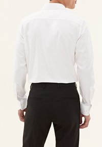 Witte blouse met lange mouwen en een puntige kraag, met knoopmanchetten en een soepele textuur, gecombineerd met zwarte, op maat gemaakte broek met achterzakken.