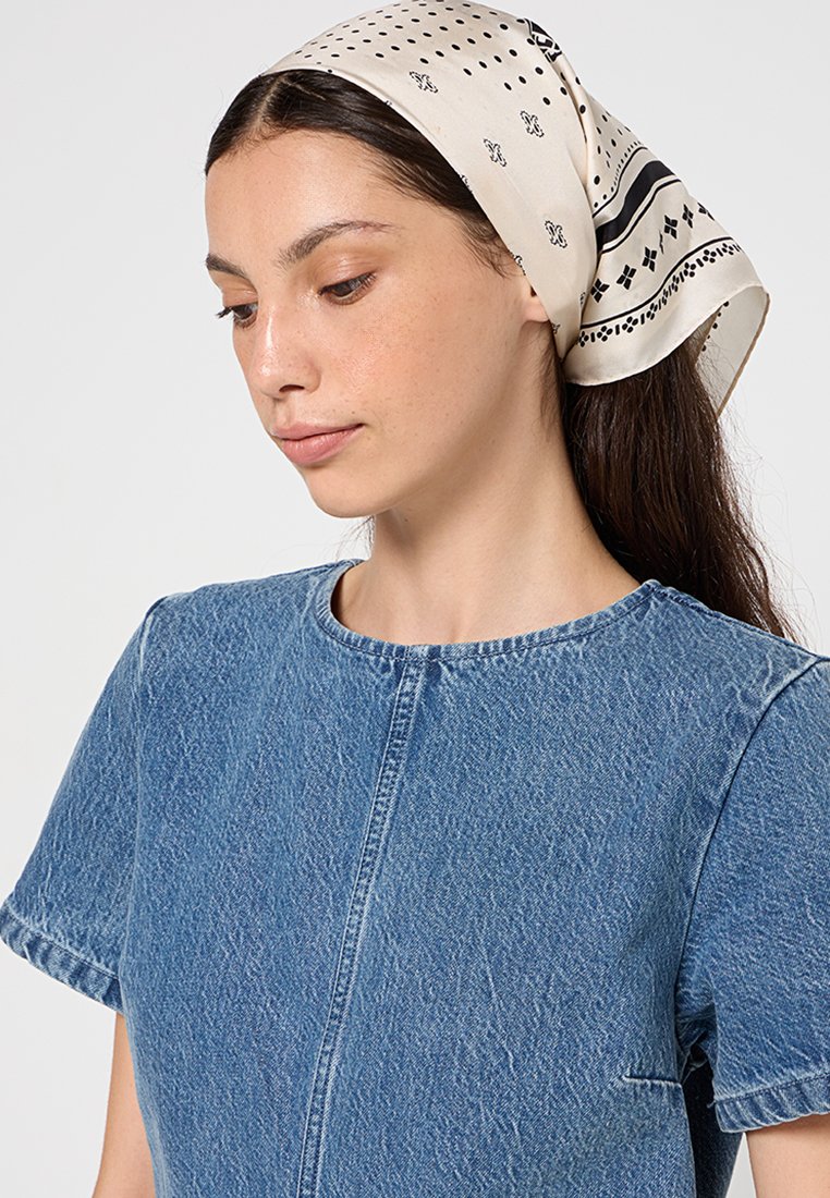 Robe en denim à manches courtes, de couleur bleu clair, en tissu texturé, avec un col rond. Une écharpe crème à motifs nouée autour de la tête.