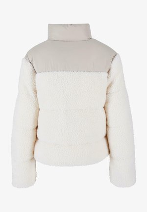 Fehér bolyhos puffer dzseki sima, világos bézs felsőrésszel. Jellemzője a magas gallér és a steppelt dizájn, amely texturált megjelenést kölcsönöz.