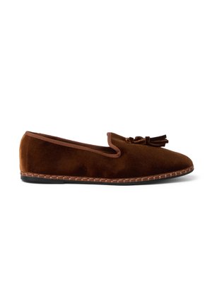 Mocasín plano de ante marrón con puntera redondeada, borlas decorativas en la parte superior y ribete cosido alrededor de la suela.