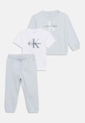 Súprava detského oblečenia obsahuje svetlomodrú mikinu, biele tričko s krátkym rukávom s logom Calvin Klein a svetlomodré elastické nohavice.