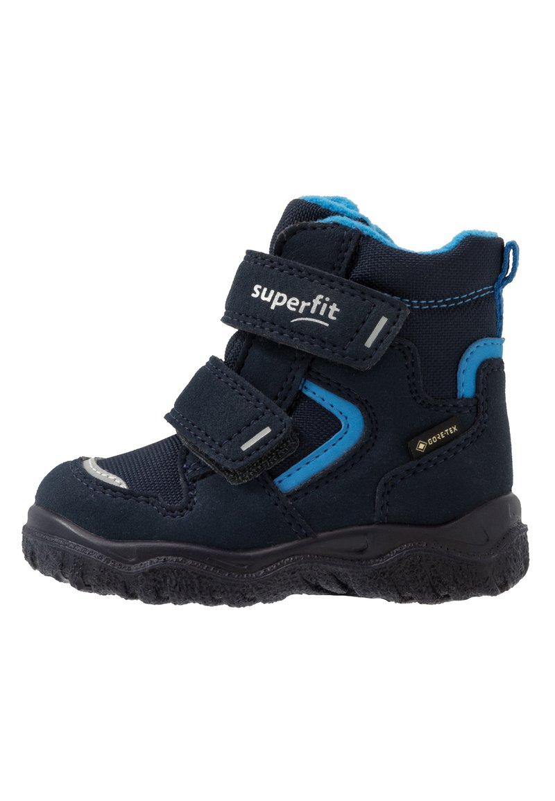 Scarponcino da trekking di un blu scuro con accenti blu, due cinghie in Velcro, suola in gomma testurizzata, impermeabile in GORE-TEX e colletto imbottito per il comfort.