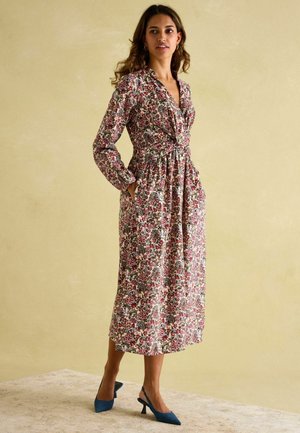 Floral long-sleeve dress with a V-neck, cinched waist, and side pockets. Features a white, burgundy, and blue pattern on a cream background.