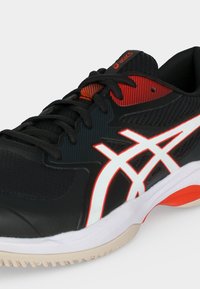 Μαύρο και κόκκινο αθλητικό παπούτσι Asics με λευκό λογότυπο, μαύρα κορδόνια και λευκή και πορτοκαλί σόλα.