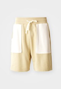 Beige bomullsshorts med ribbet midje, hvite lommedetaljer, snøring og en avslappet passform. Glatt stoffstruktur.