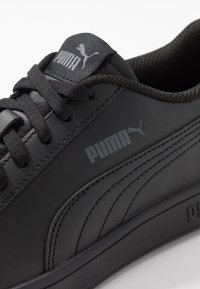 Svarta lädersneakers med rundad tå, texturerade sidopaneler, platta snören och en framträdande Puma-logotyp på tungan och sidan.