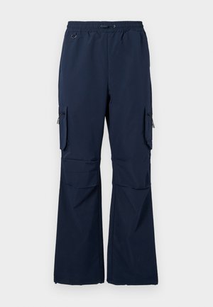 Pantalons cargo navy en tissu léger avec taille à cordon, deux poches latérales et poches cargo zippées sur les deux jambes.