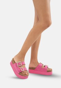 Roze platform sandalen van suede, met twee gespen versierd met rhinestones. Kurken zool en een getextureerde rubberen loopzool.