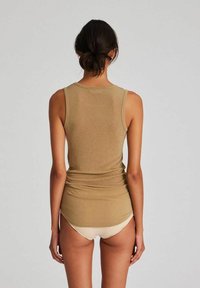 Peene tank top, mis on valmistatud pehmest kangast, ümarate kaeluste ja kitsa silueti ning heledate pükstega.