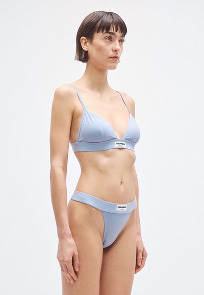 Conjunto de sujetador y tanga de algodón azul claro, con tirantes finos, textura suave y una cinturilla elástica con marca. Diseño sencillo con detalles mínimos.