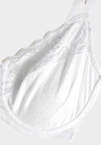 Weißer BH aus glattem Material mit kleinen gepunkteten Mustern und Spitzendekor am Rand, das die weiche Textur und die Design-Details betont.