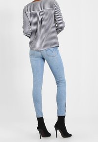 Randig svart och vit blus med puffärmar, matchad med ljusblå skinny jeans och svarta högklackade ankelstövlar.