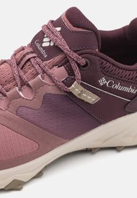 Lilla og mauve terrengsko med teksturert mesh og glatte skinnakenter, med flettede snører og en beige merkeinnsats.
