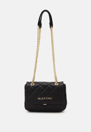 Schwarze gesteppte Lederhandtasche mit einem goldenen Kettenriemen. Verfügt über einen Magnetverschluss und ein geprägtes Logo auf der Vorderseite. Kompakte rechteckige Form.