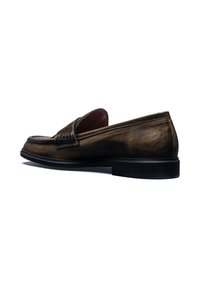 Mocassin en cuir marron avec un bout arrondi, des coutures détaillées et une accent texture sur le devant. Il est doté d'une semelle en caoutchouc noire.