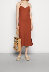 Ruskoto värvi ribatud midi kleit õhukeste rihmadega ja liibuva bodiga. Kombineeritud punutud õlgkoti ja värviliste ruudukujuliste mustritega ning platvormsandaalidega.