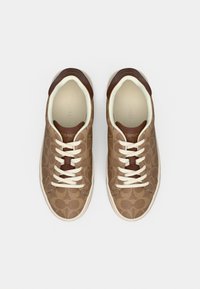 Bruine canvas sneakers met patroon, bruine lederen accenten, witte veters en een crèmekleurige binnenkant. Afgeronde neus en rubberen zool.