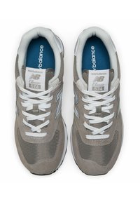 Harmaat New Balance Classic 574 -tennarit sisältävät mokkanahka- ja verkko-yläosan, valkoiset nauhat ja sinisen sisäpohjan, jossa on hopeisia yksityiskohtia sivuilla.