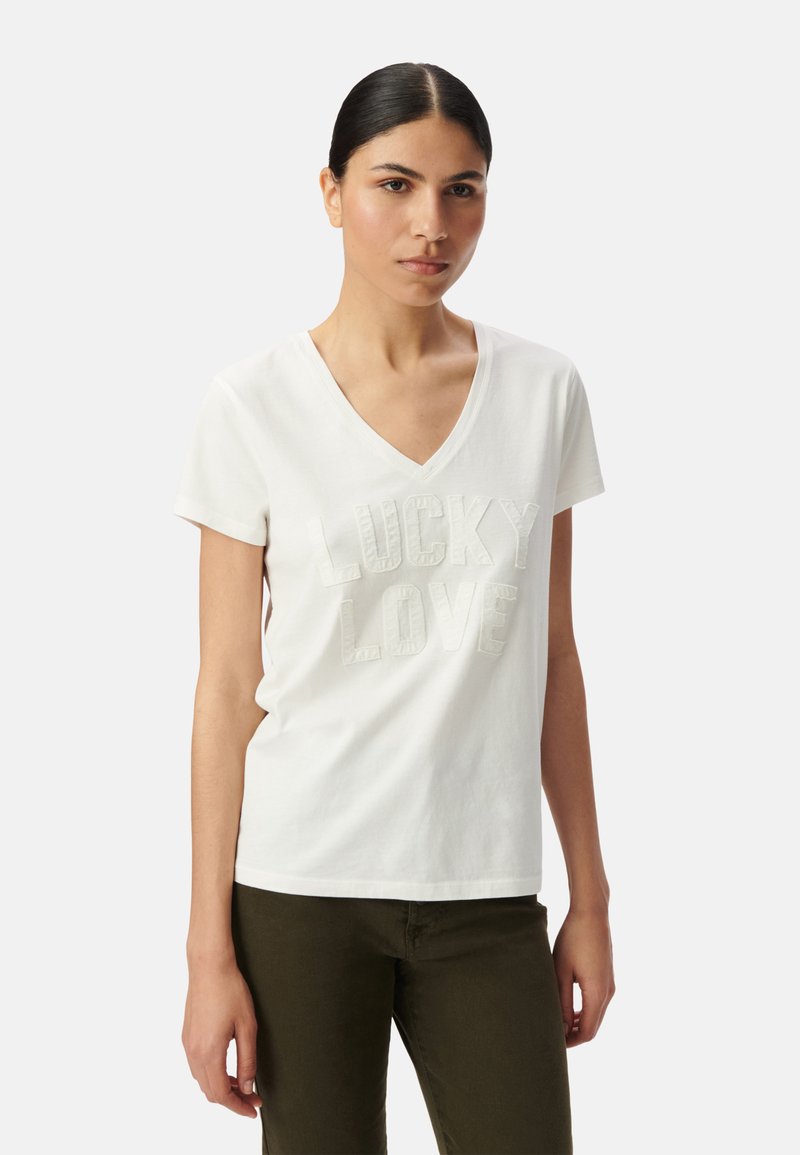 Camiseta de algodón blanca con cuello en V y mangas cortas, con un diseño de texto en relieve "LUCKY LOVE" en el centro.