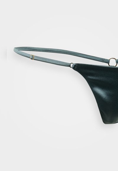 Schwarzer Bikini-Slip mit metallischem Glanz, schmale Träger und goldfarbene Beschläge. Glatte Textur, minimalistische Bedeckung.