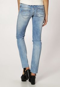 Vaqueros skinny de color azul claro con efecto desgastado, que cuentan con dos bolsillos traseros con costuras decorativas y una cintura de altura media.