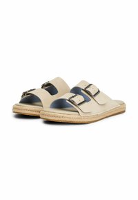 Sandali in suede beige con doppie cinghie in argento, suola in espadrille e design aperto sulla punta. Presentano una soletta testurizzata e un rivestimento morbido.