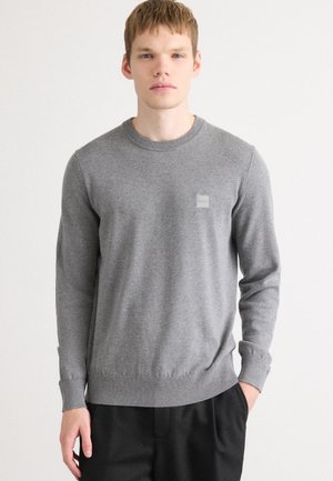 Gray knit sweater with long sleeves, round neckline, ribbed cuffs and hem, featuring a small branded patch on the chest.