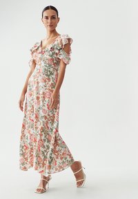 Robe maxi avec motif floral en rose, vert et orange. Dispose de manches volantées et d'une taille ajustée. Fabriquée en tissu léger.