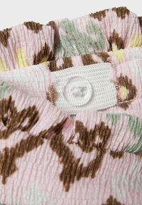 Bloemmotief stof in roze, groen en bruin met een gestructureerd oppervlak. Heeft een witte knop genaaid op de binnennaad.
