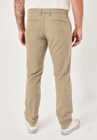 Khakihosen mit slim fit, aus einem glatten Baumwollmix, verfügen über Gesäßtaschen und einen normalen Bund. Tragen Sie dazu weiße Sneaker.