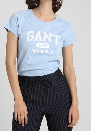 Jasnoniebieski bawełniany t-shirt z nadrukiem "GANT 1949 NEW HAVEN" w kolorze białym. Do tego czarne spodnie w prążki z regulowanym troczkiem w pasie.