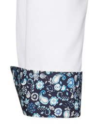 Cuff di camicia bianca con un motivo floreale blu navy, caratterizzato da fiori blu e bianchi e design paisley; tessuto di cotone con una consistenza liscia.