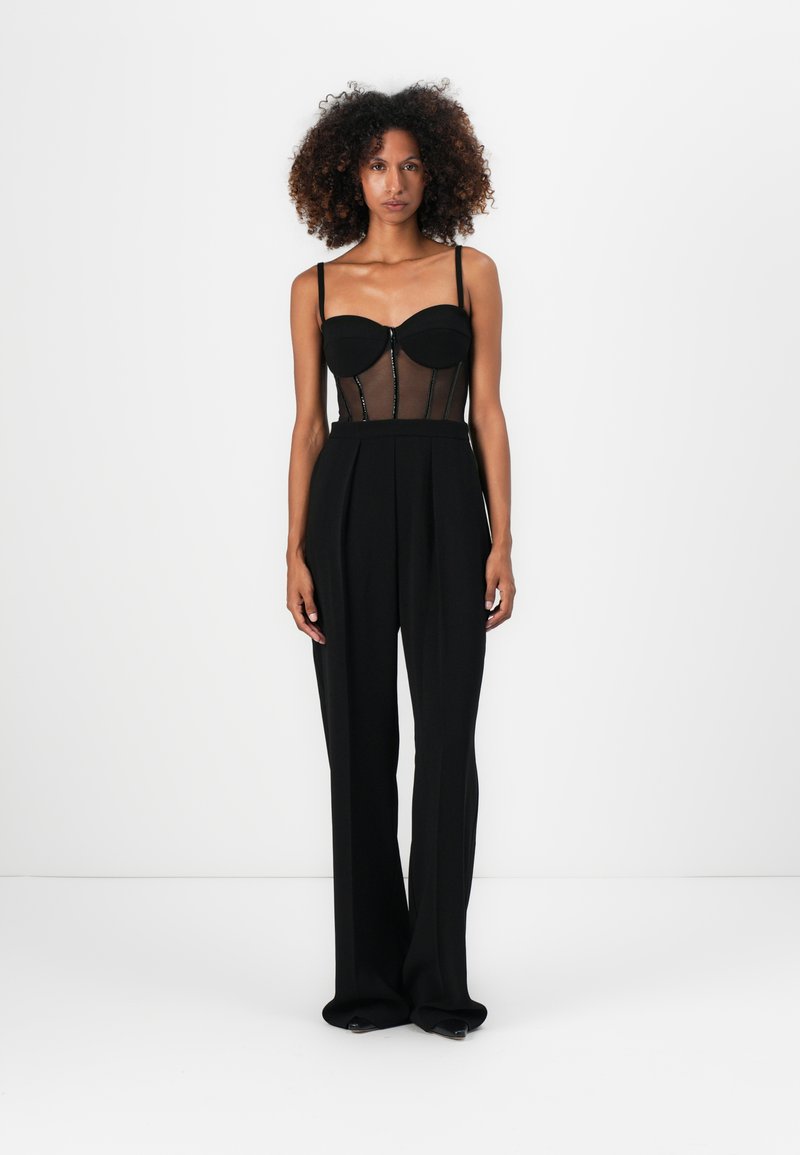 Schwarzes Zweiteiliges Outfit mit einem taillierten, durchsichtigen Oberteil mit Cup-Details und weiter geschnittenen Hosen. Glatte Textur mit minimalen Hardware-Akzenten.