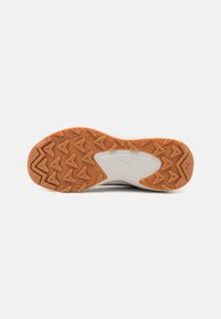 Puma shoe outsole in orange and white, featuring a textured pattern for grip and durability. Accents include a central logo and angular details.