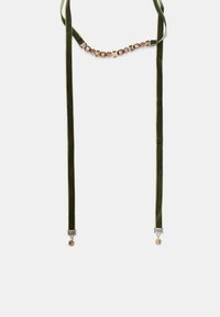 Zelený sametový choker s metalickými akcentmi a dekoratívnymi drahokamami. Hladký povrch s nastaviteľnou dĺžkou; obsahuje lesklý zavesený prívesok.
