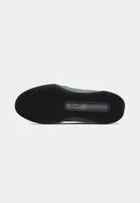 Podrá obuvi Nike má textúrovaný čierny gumový povrch so zigzagovým vzorom a centrálnym kruhovým logom. Hladké okraje a zaoblený tvar.