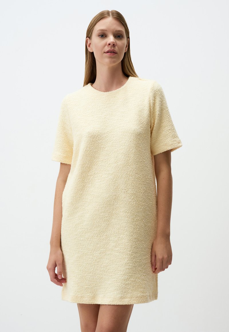 Robe jaune à manches courtes en tissu texturé, dotée d'un col rond et d'une coupe décontractée, se terminant juste au-dessus des genoux.