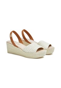 Sandalias de cuña con un upper de tejido trenzado en color crema, diseño de punta abierta y tiras de goma en tono marrón. Suela de plataforma texturizada similar al yute.