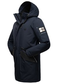 Marinblå parka-jacka med huva, som har ett mysigt innerfoder, två framfickor och ett framträdande logopatch på ärmen.