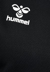 Schwarzer Stoff mit einer Netzstruktur, versehen mit einem weißen Hummel-Logo und einer stilisierten Biene. Die Oberfläche wirkt glatt und strapazierfähig.