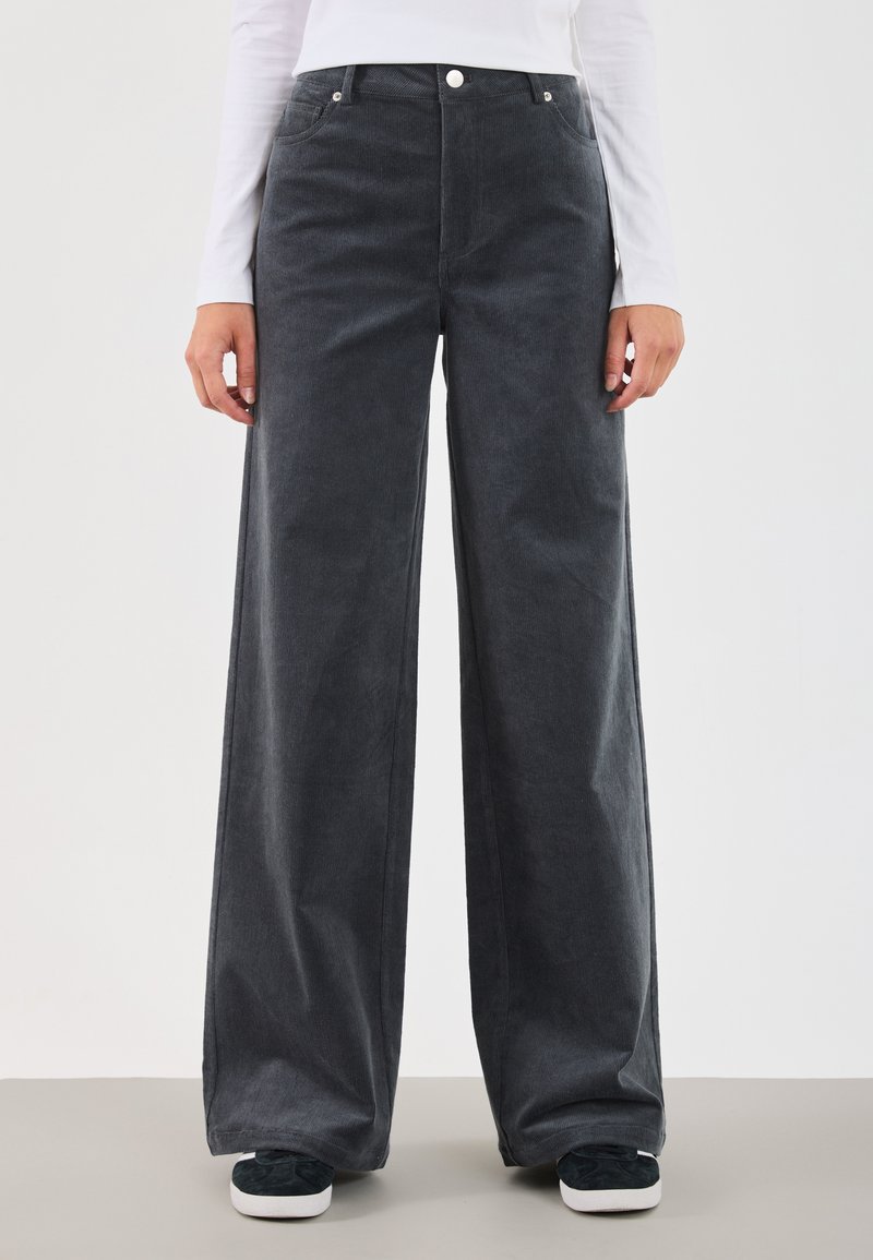 Pantalons en velours côtelé à jambes larges de couleur gris foncé, avec un tissu texturé, une taille haute, des poches avant et des détails en métal sur les boutons.
