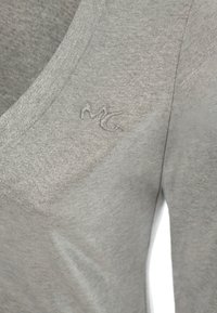 Maglietta grigia con design a V, realizzata in un tessuto testurizzato con una leggera lucentezza. Include un logo ricamato "MG".