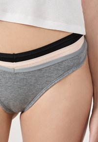 Graue gerippte Unterwäsche mit niedrigem Bund, ausgestattet mit schichtweisen elastischen Taillenbändern in Schwarz, Rosa und Grau. Glatte Textur.