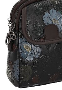 Sort håndtaske med blomstret prægning i grå, blå og vinrøde blomster. Har lynlås og en lille dekorativ charme. Glat, blank tekstur.