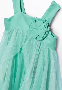 Abito verde menta con corpetto aderente, spalline sottili e gonna in tulle sovrapposta; decorato con un fiore di tessuto sulla spalla.