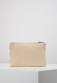 Beżowa kopertówka z materiału płóciennego z zamkiem błyskawicznym, o fakturowanej powierzchni i ozdobnym łańcuszkiem po boku.