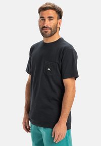 Black cotton t-shirt with short sleeves and a chest pocket featuring a small logo. Smooth texture, standard fit, crew neckline.
